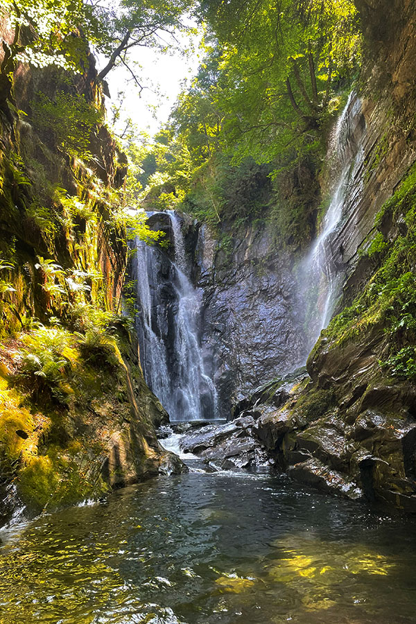 Wasserfall inmitten steiler Felsen und grüner Vegetation im Val Grande Canyon im Tessin