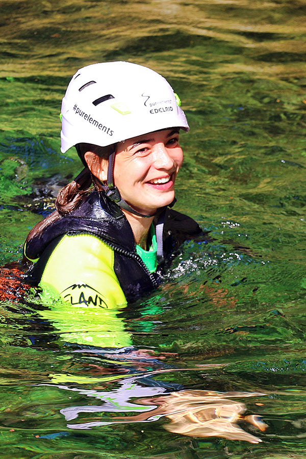 Lachende Frau mit Helm beim Canyoning im Tessin – nachhaltiges Outdoor-Erlebnis mit purelements®