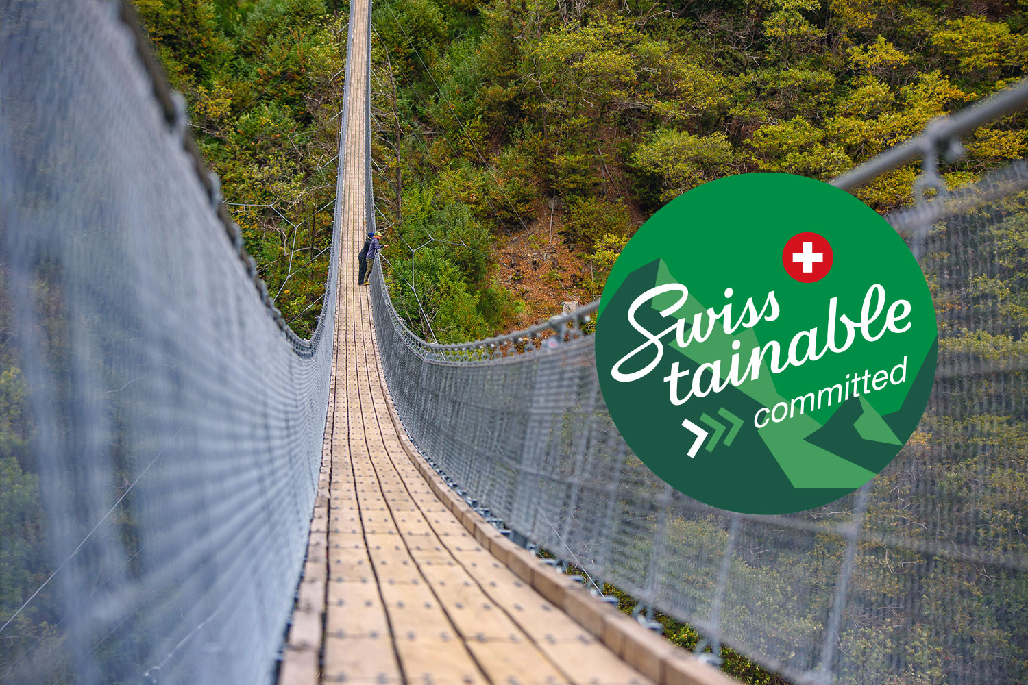 Person auf einer Hängebrücke in der Schweizer Natur mit Swisstainable-Label – Symbol für nachhaltigen Tourismus in der Schweiz